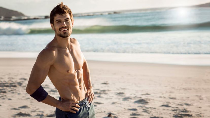 handsome man smiling beach sunset swim trunks