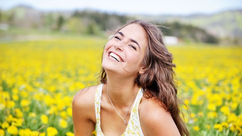 Laughing woman in dandelion spring meadow