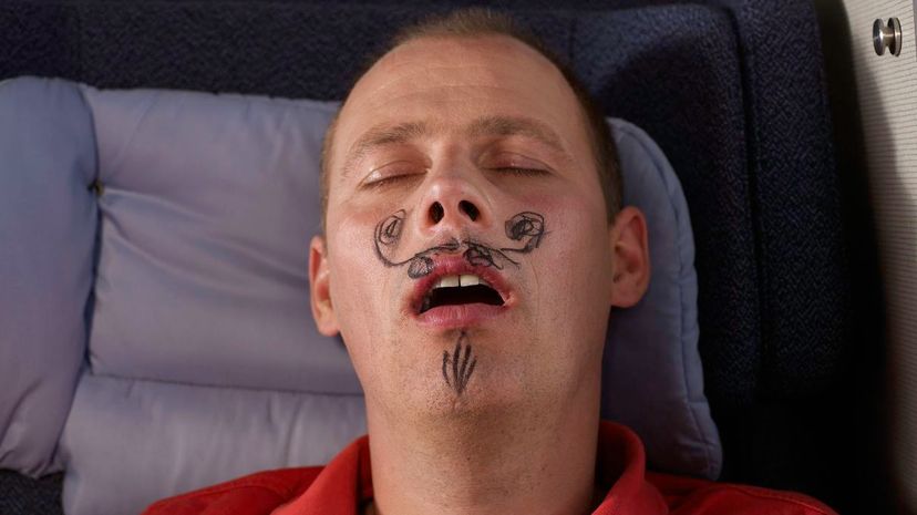 Sleeping man with drawn moustache