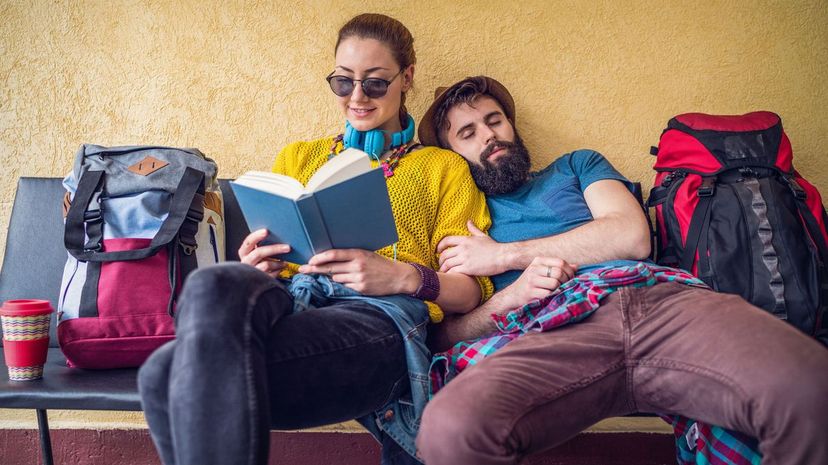 Backpacker couple at the train station reading book