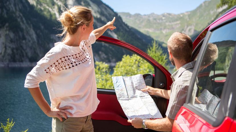Couple of tourist with rental car reading map-Road trip