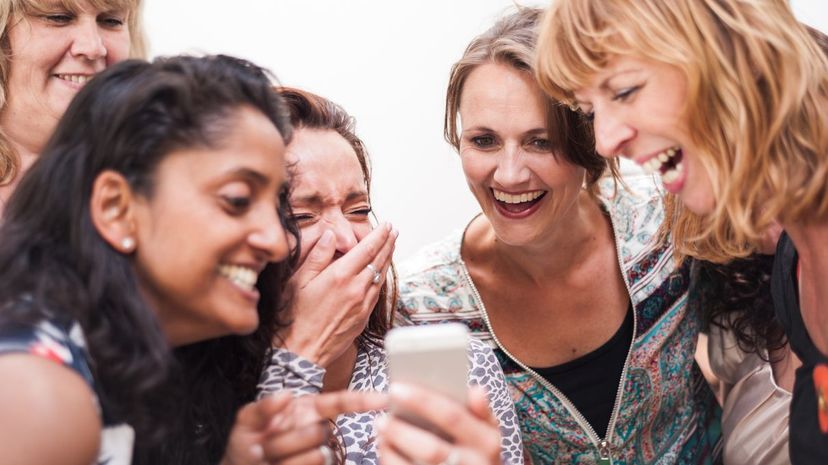 Friends laughing at meme on smartphone