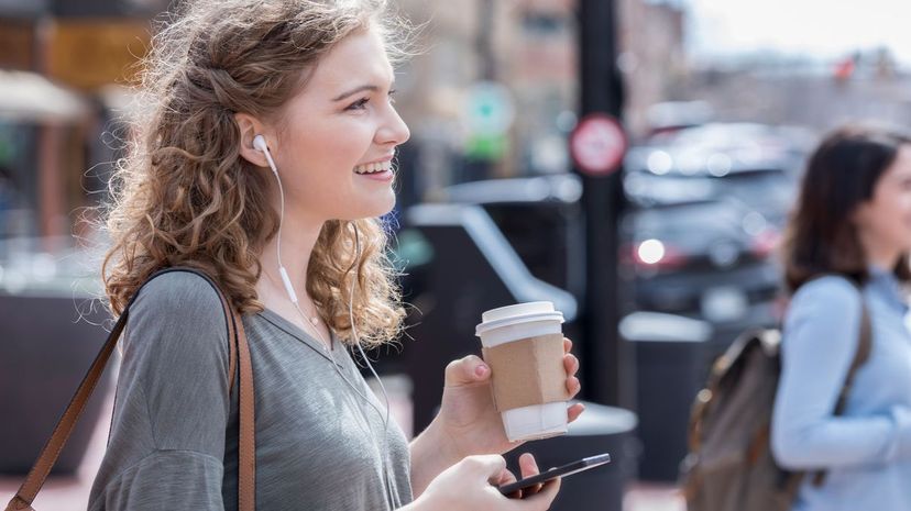 Woman listens to music and holds a cup of coffee