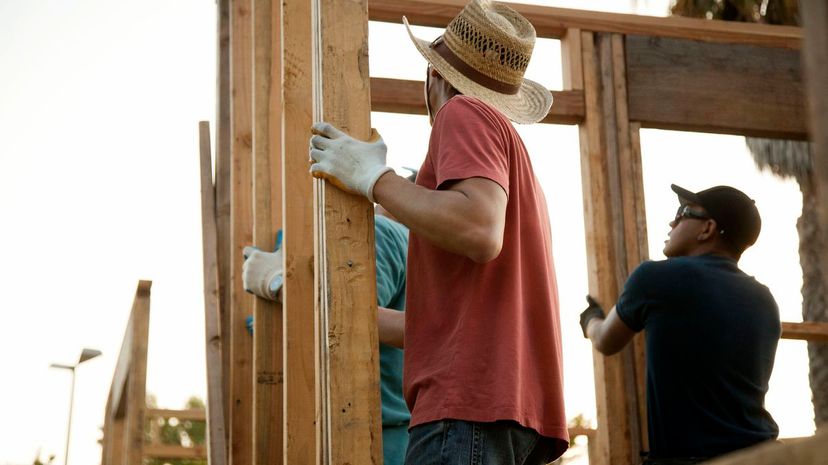 Construction workers adjusting house frame