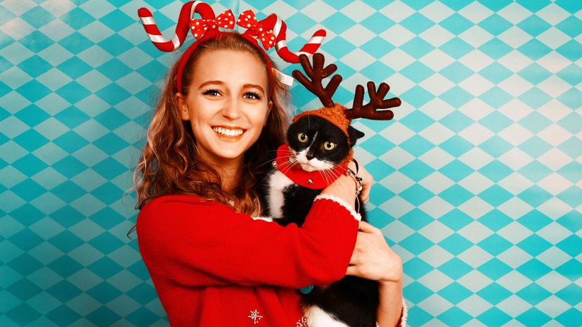 Girl in Christmas ugly sweater holding cat