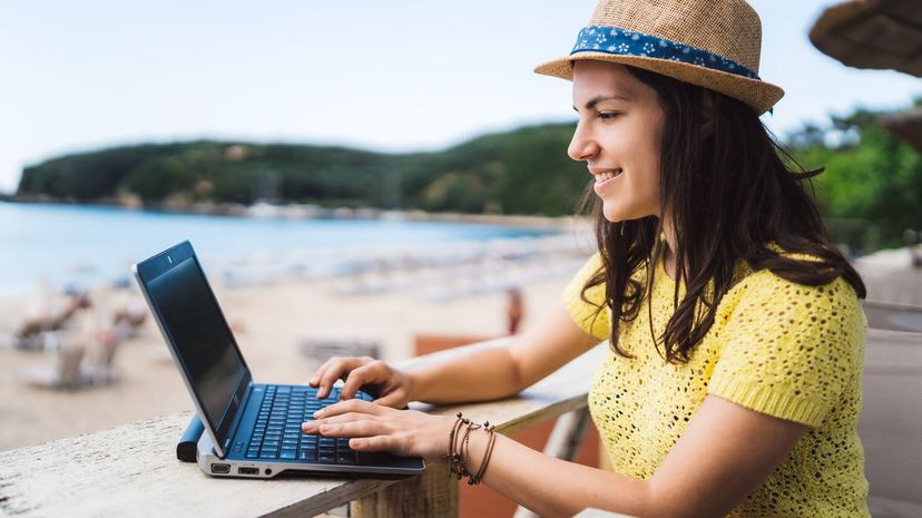Young woman is using laptop in beach bar cafÃ©