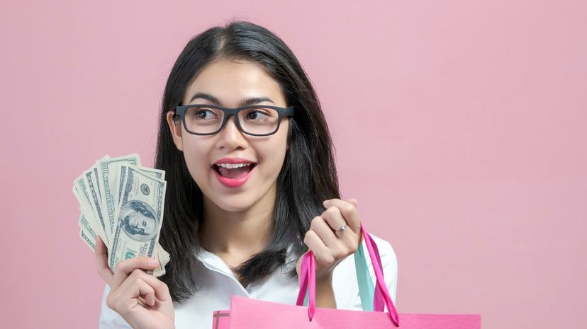 Woman enjoying thinking about using money for shopping in the shopping mall