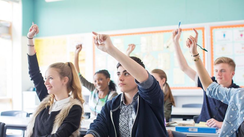 Students raising arms during lesson in classroom