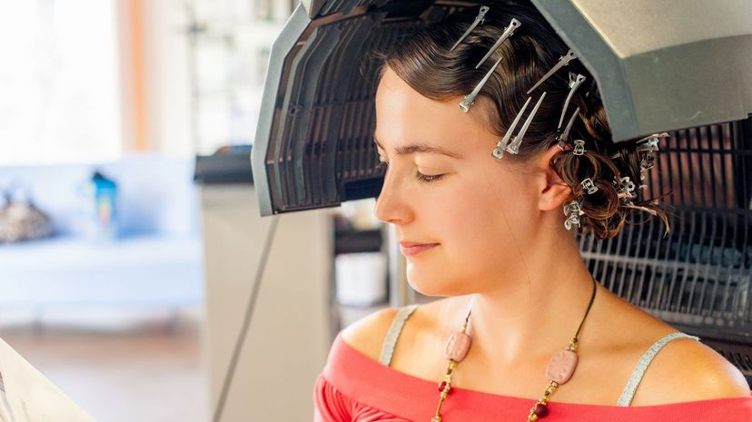 Young woman relaxing while waiting under the dryer in the Hair salon