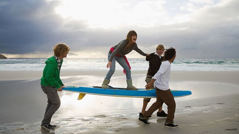 Teens carrying surfboard