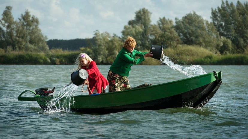 Women bailing water out of boat in lake