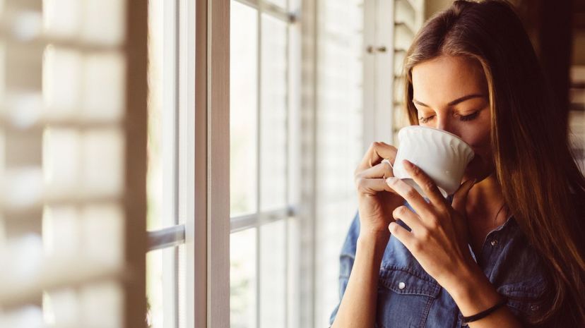 Woman drinking tea by window