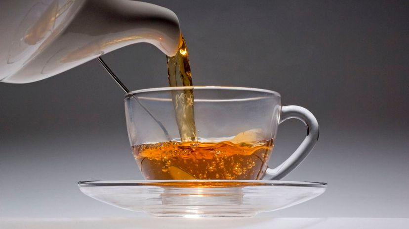 Tea pouring from a white china pot into glass cup