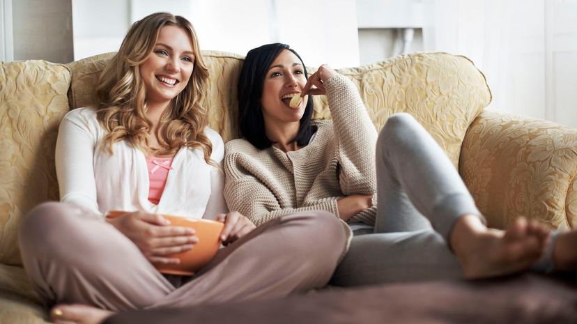Women sitting on sofa watching a movie and eating snacks