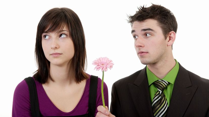 A boy trying to give a flower to a girl