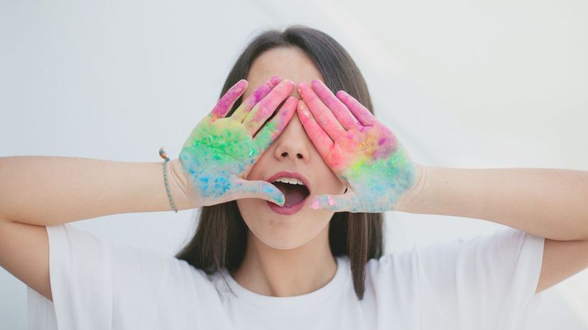 Girl covering eyes with dirty painted hands