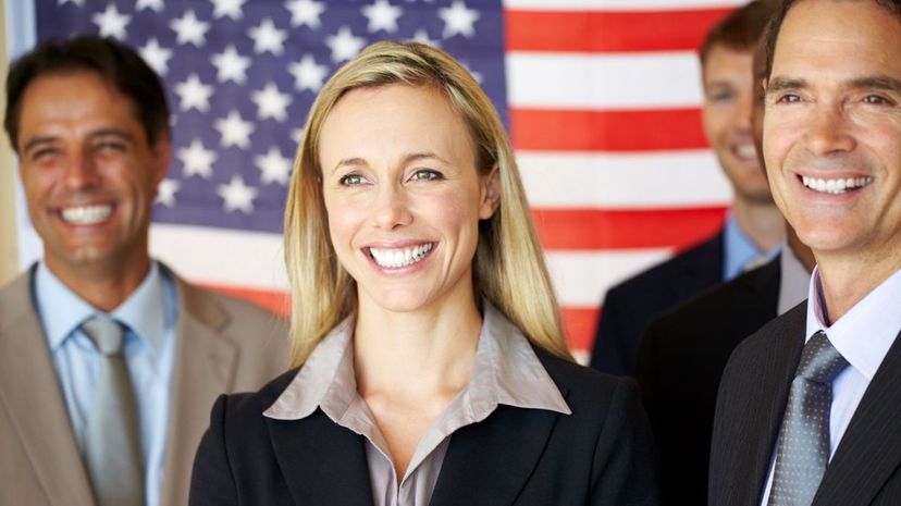 Confident executives smiling in front of flag