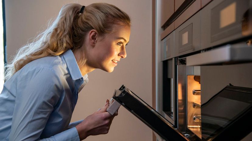 Woman checking food in the oven