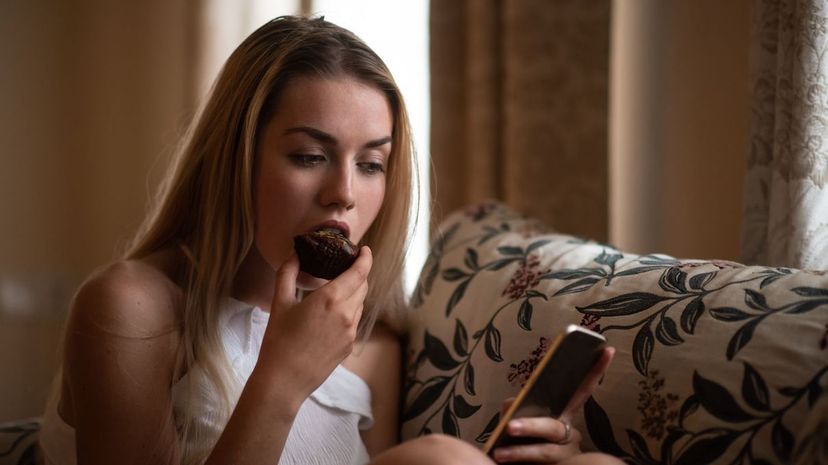 Teenage woman having bite of chocolate cupcake