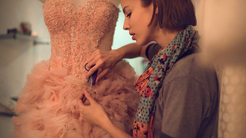 Clothing designer cutting material on a dress in workshop Fashion