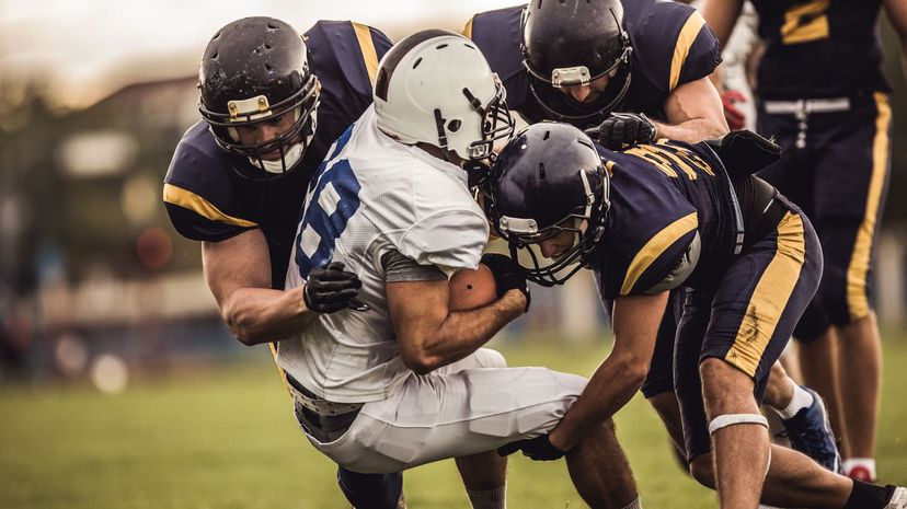 American football players tackling opposite's team quarterback