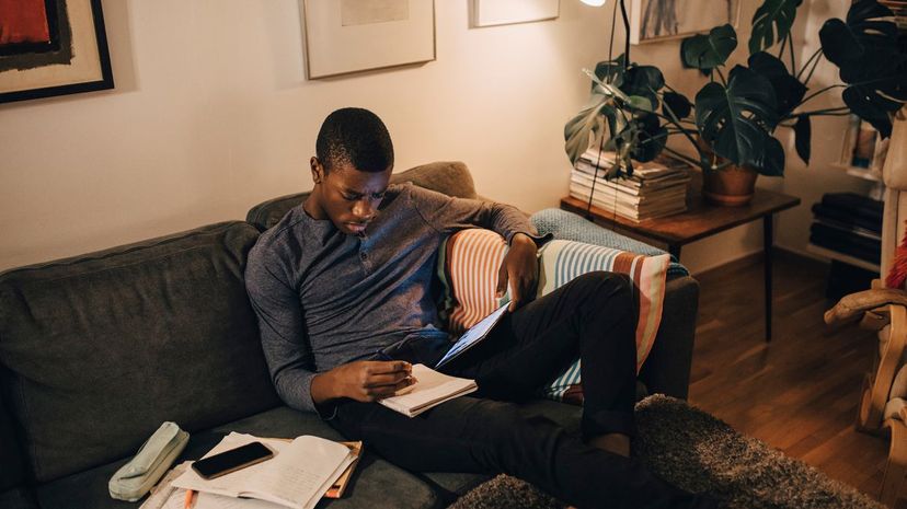 High angle view of boy using digital tablet while studying on sofa at home