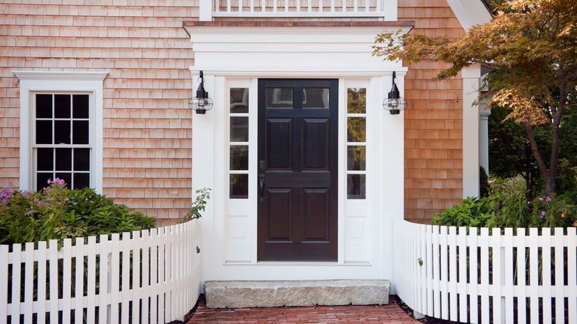 Entryway of brick New England home with picket fence