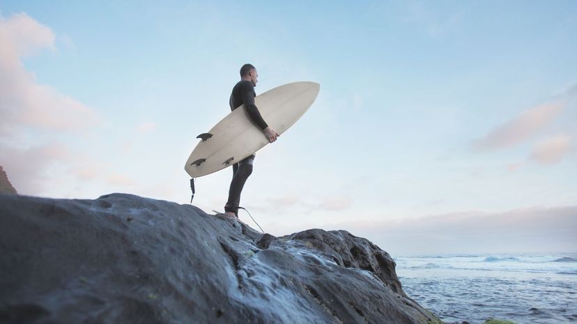 Surfer standing on rock