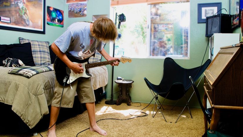 Teen playing guitar in bedroom
