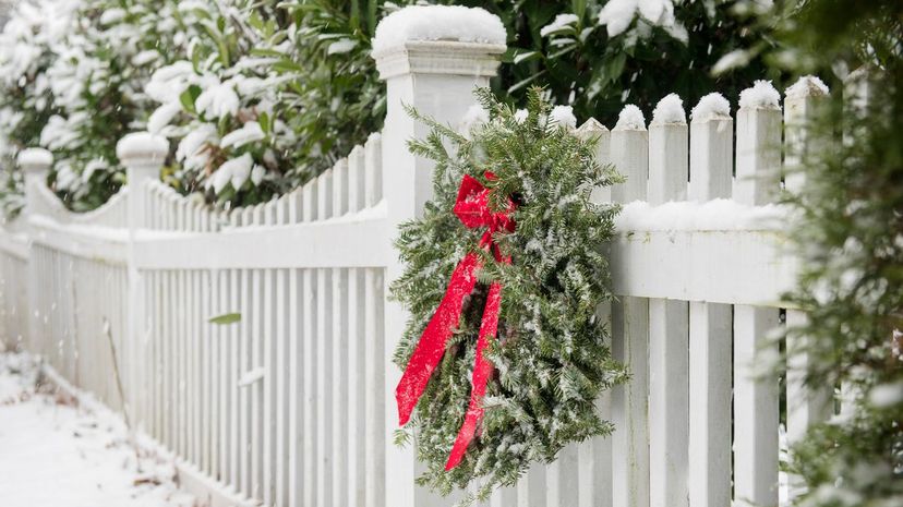 Q34-Christmas wreath hanging on white fence covered in snow