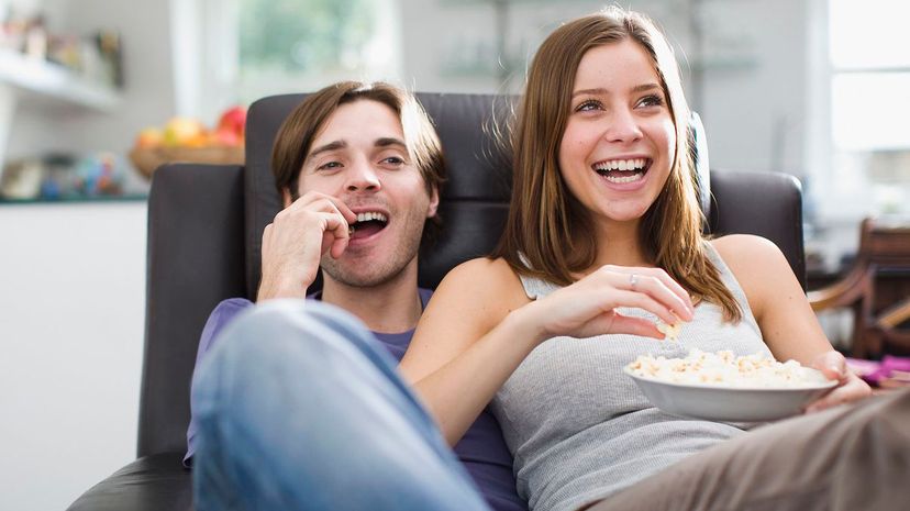 Couple watching television and eating popcorn