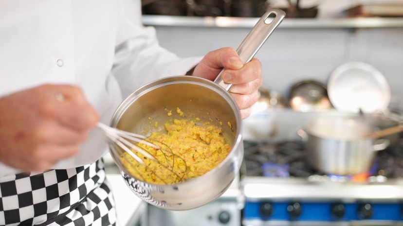 Chef whisking scrambled eggs in kitchen