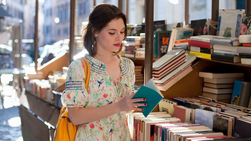 Young woman flipping through book at bookstall