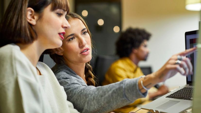 Coworkers discussing over computer in office