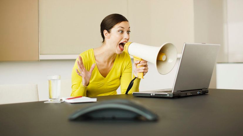 Businesswoman yelling at laptop with bullhorn