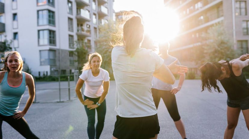 Fitness Instructor Warming Up With Class Outdoors