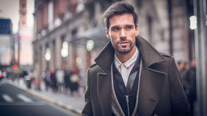attractive man in city with brown coat scruffy
