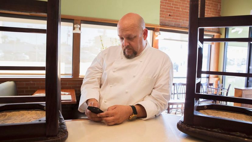 Chef using cell phone in empty restaurant