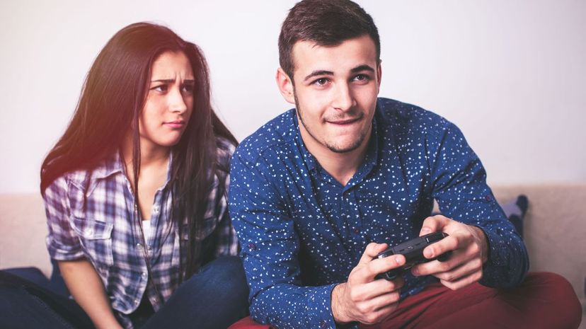 Man playing video games while his girlfriend is getting mad at him