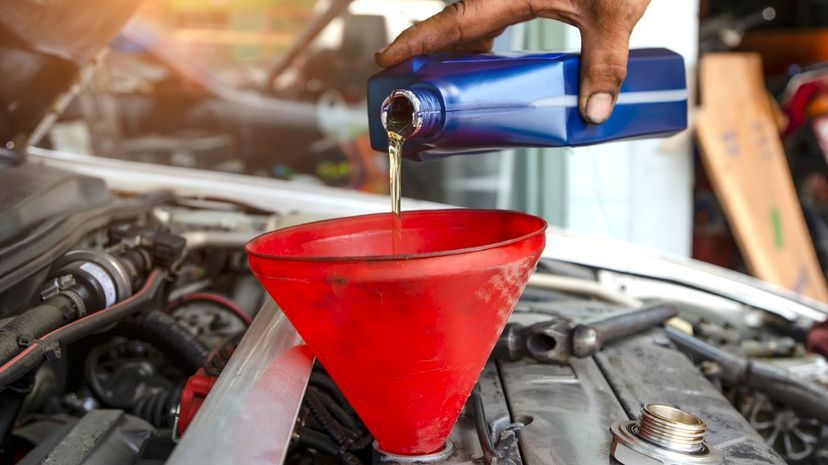 Car mechanic replacing and pouring fresh oil into engine at maintenance repair service station