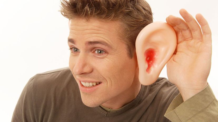 Man cupping hand over big ear