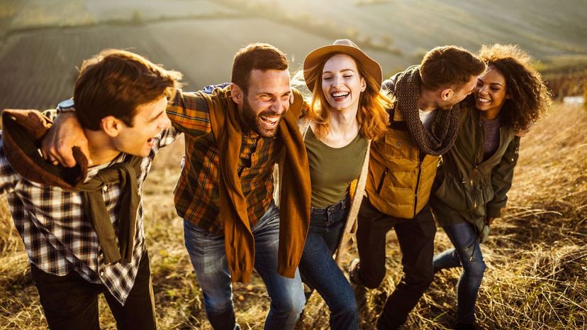 Young cheerful friends walking up the hill in autumn day