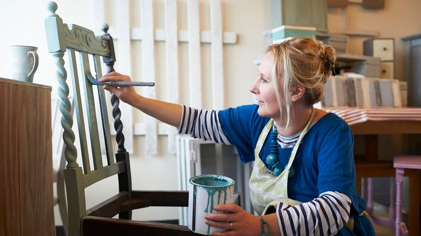 Woman painting chair in workshop