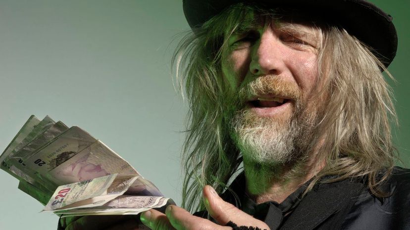 Scruffy mature man holding British pound notes