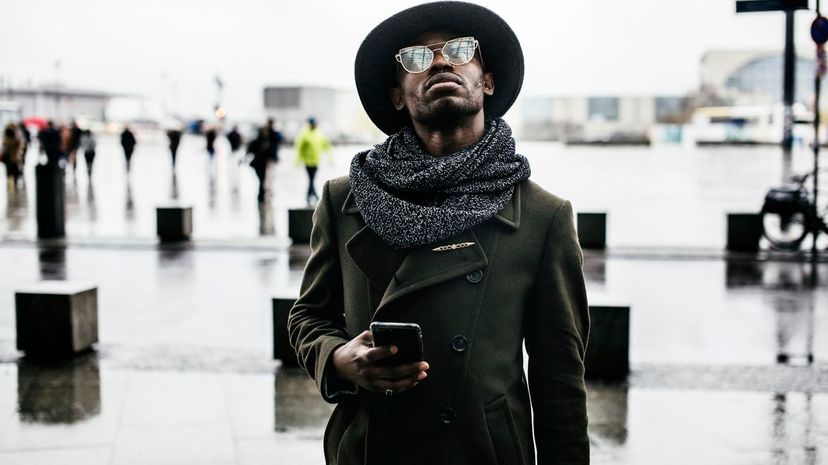Black Man Looking up While Holding Smartphone Fashion