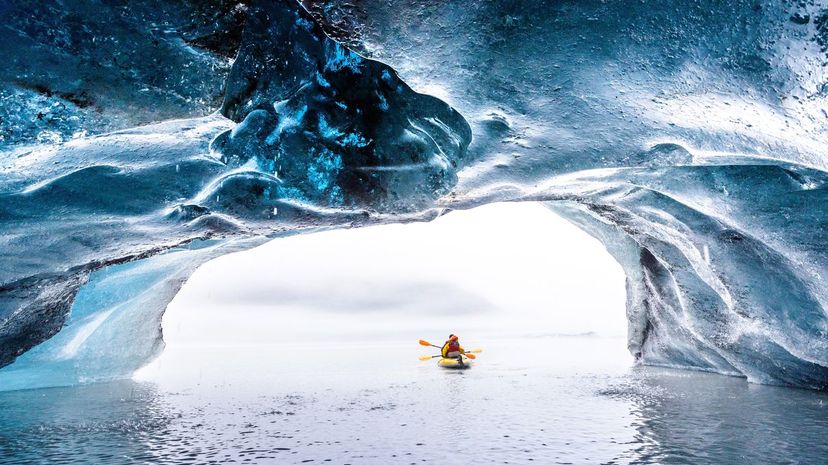 Tourists are kayaking out of the brilliant blue ice cave, Valdez, Alaska
