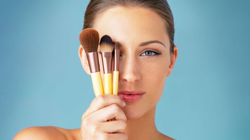 Woman holding makeup brushes in front of her eyes