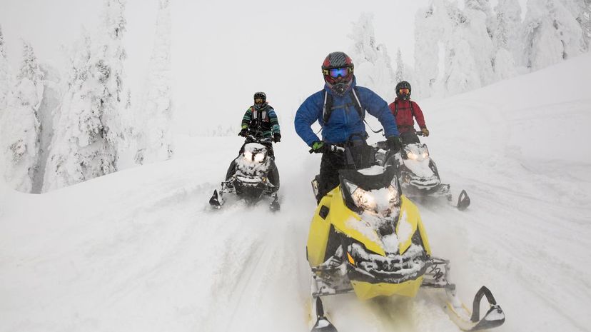 Men snowmobiling in remote snowy woods