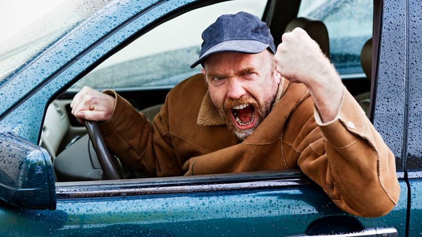 Furious male driver shakes his fist out of car window