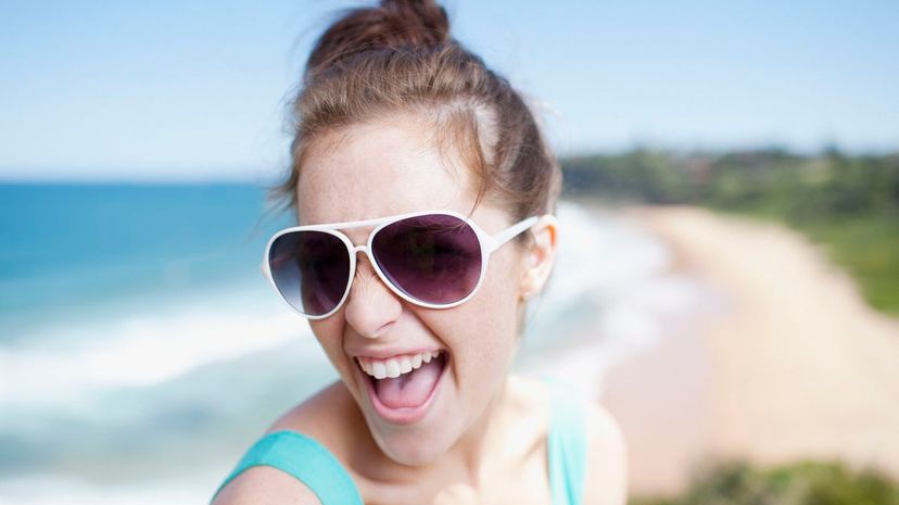 Woman in sunglasses laughing with ocean in background